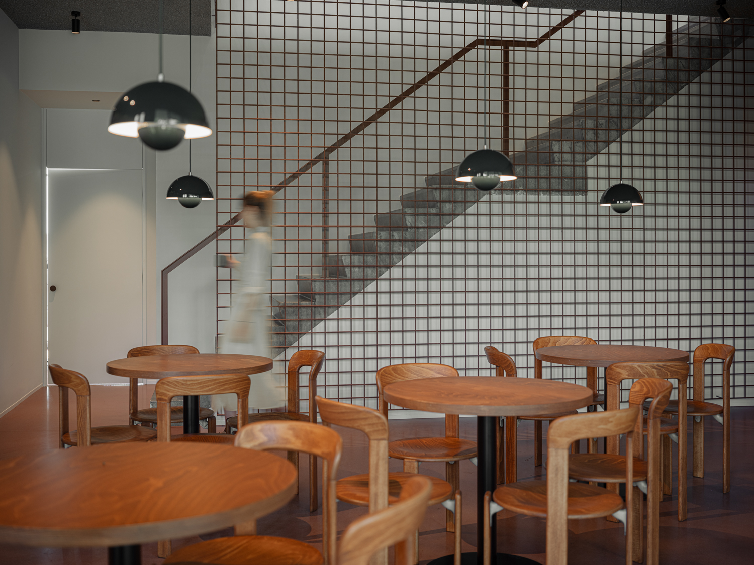 Cafetaria met houten tafels en trap op de achtergrond